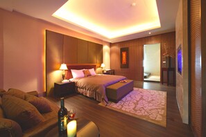Un dormitorio moderno con una cama grande, mesitas de noche, un pouf y una alfombra decorativa.