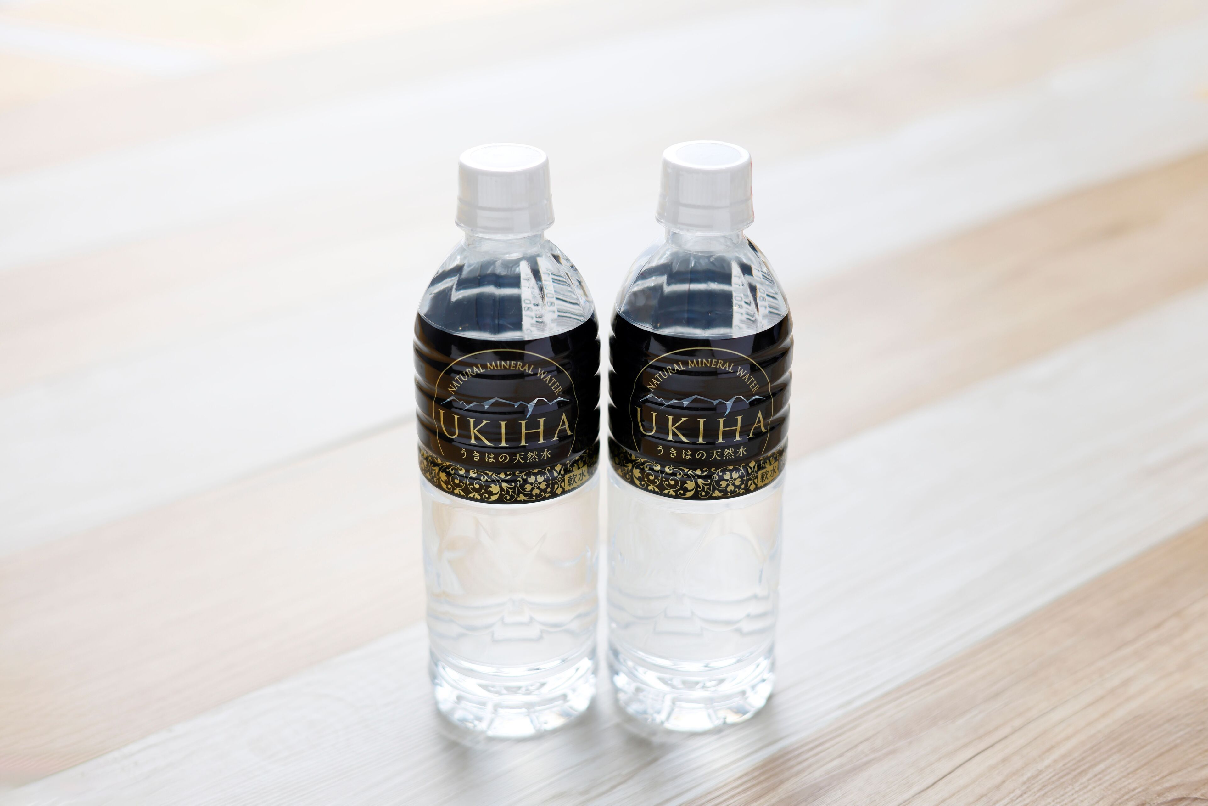 Two clear water bottles with labels on a wooden surface.