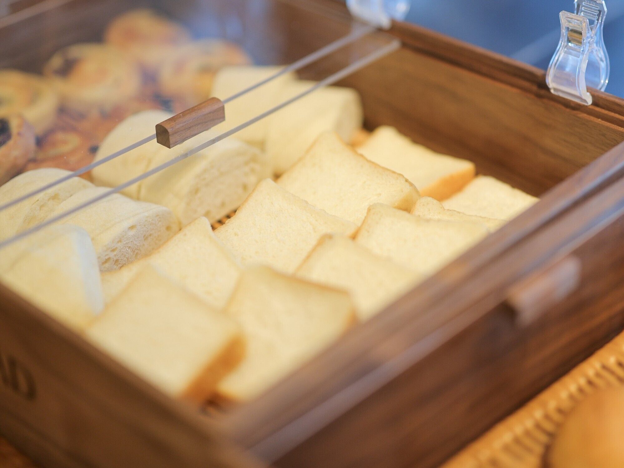 A wooden bread display case with multiple slices of bread.
