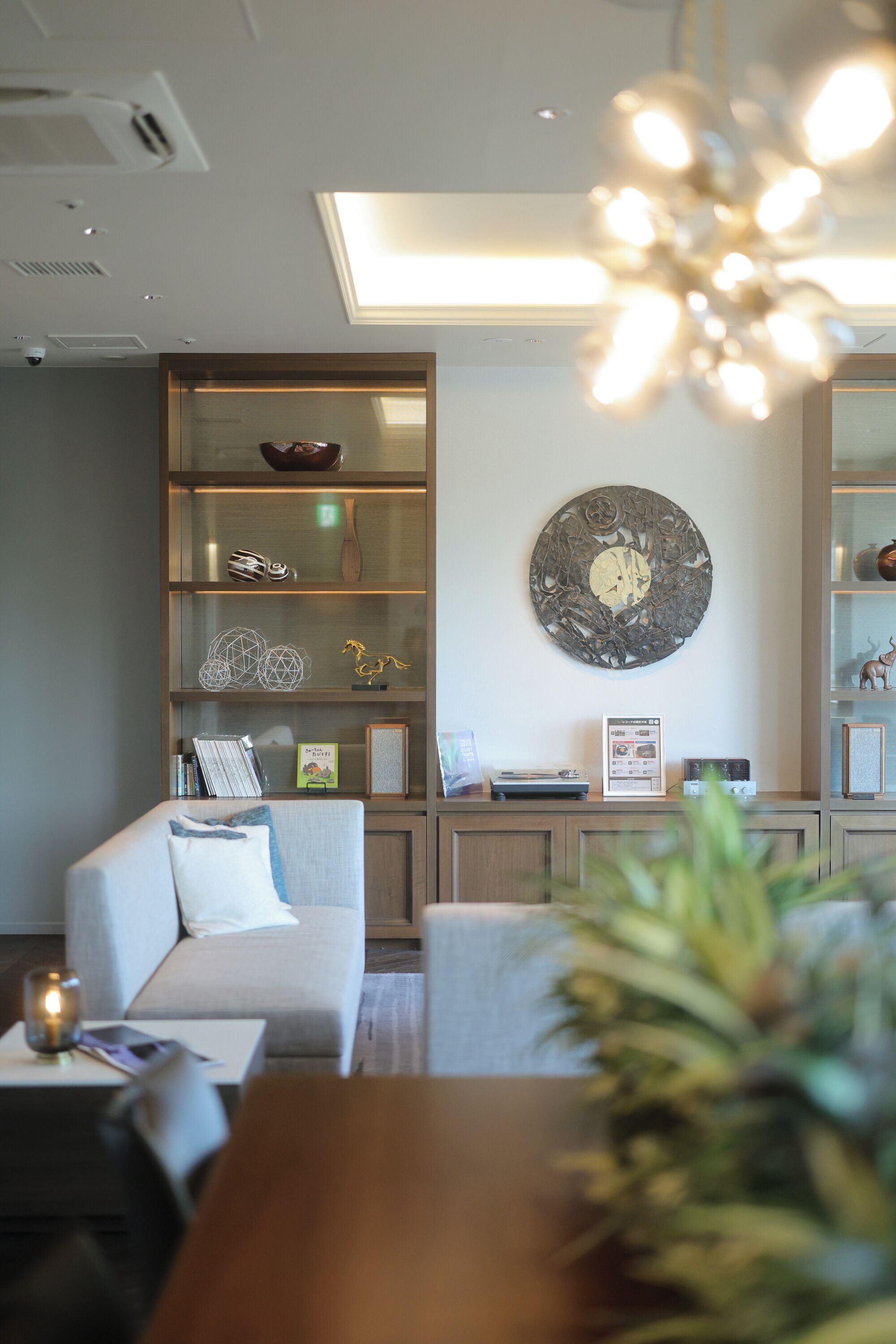 A modern living room with a sofa, a coffee table, a bookshelf, and a decorative wall piece.