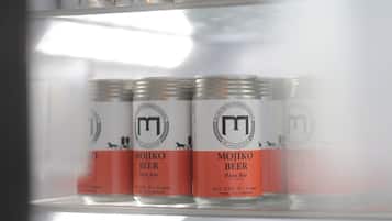 A refrigerator stocked with cans of beer, including Mojiko Beer and Asahi.