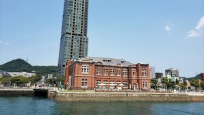 Un edificio frente al agua, con un rascacielos moderno y una construcción de ladrillo tradicional.