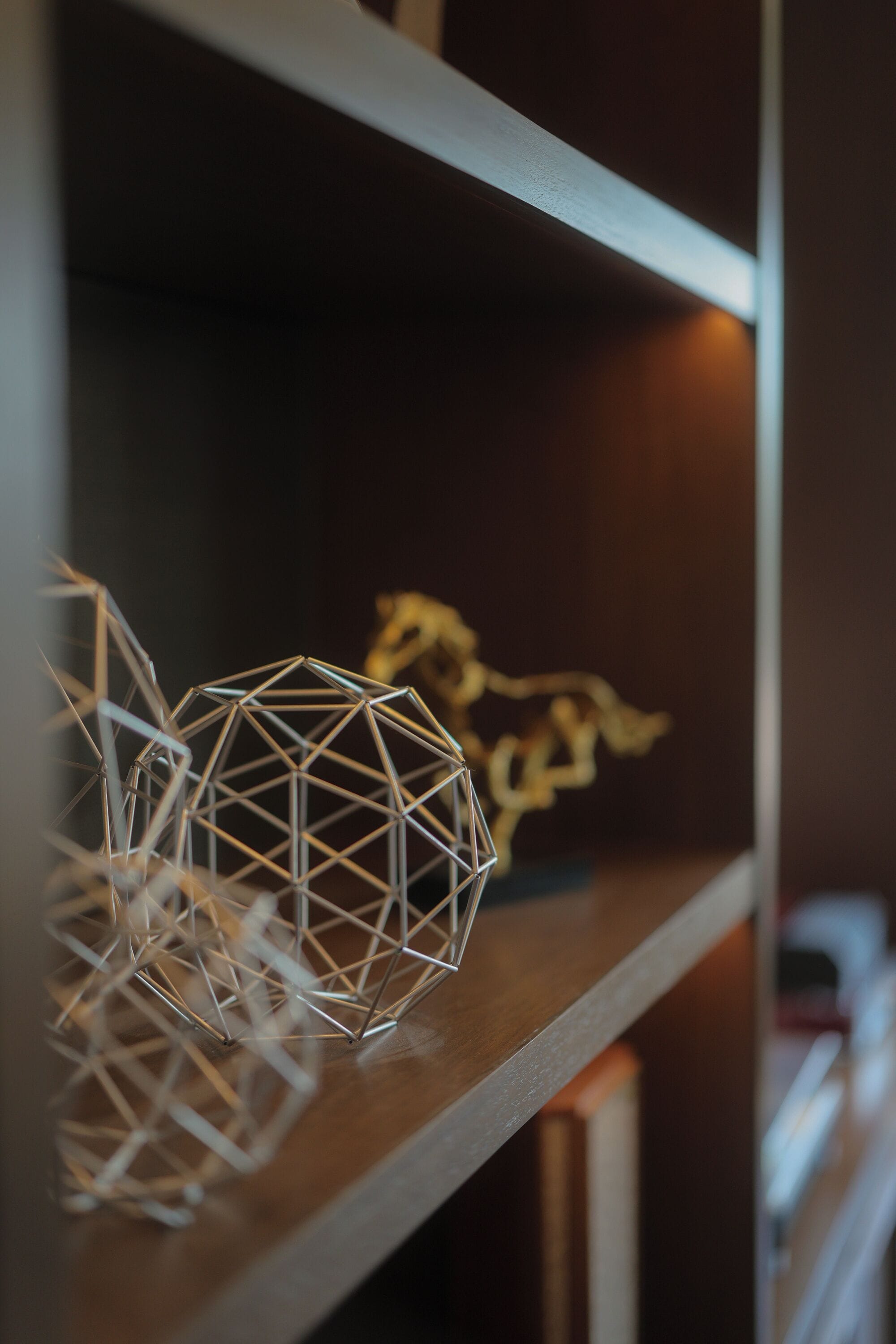Une étagère avec des sculptures métalliques aux formes géométriques, sur un fond flou.