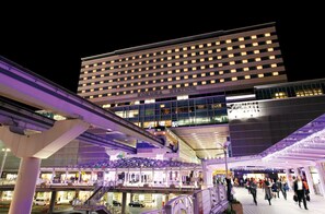 Un bâtiment moderne, sur lequel on peut lire l’inscription « Gare de Kokura », et une passerelle piétonne couverte.