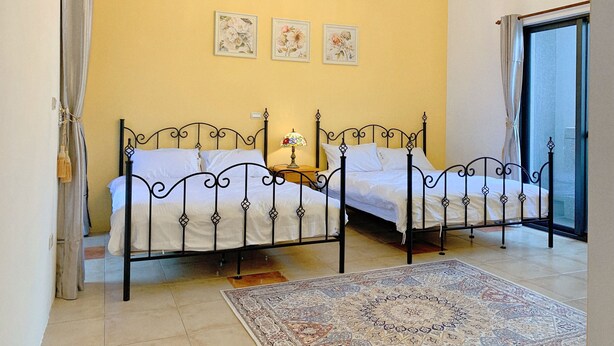 A double bed with a metal frame, a bedside table with a lamp, and a patterned rug on a tiled floor. - The Awesome Manor (Ji'an)
