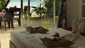 Habitación de hotel con vista a la playa, un comedor con sillas y una mesa, y una cama con toallas.