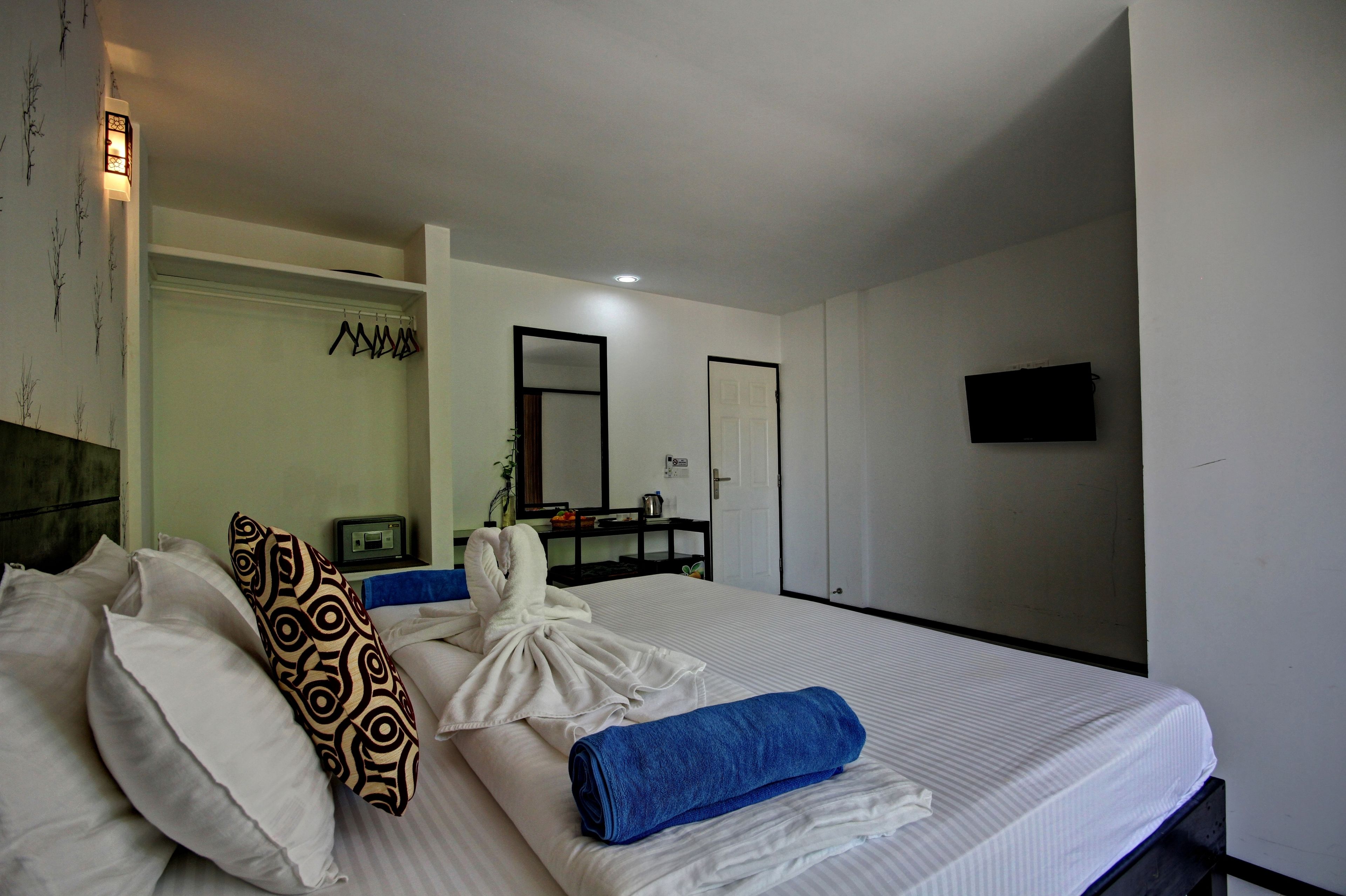 A hotel room with a neatly made bed, a robe, and a blue towel.