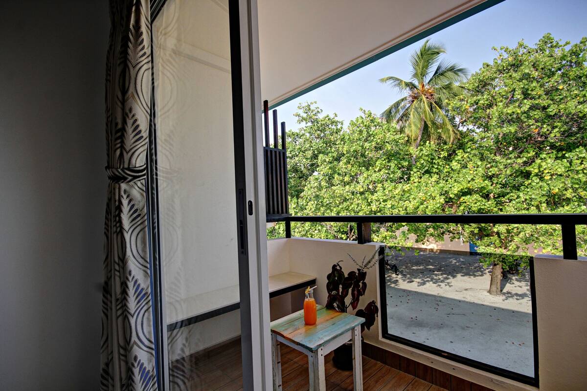 Un balcon avec vue sur une plage et des palmiers.