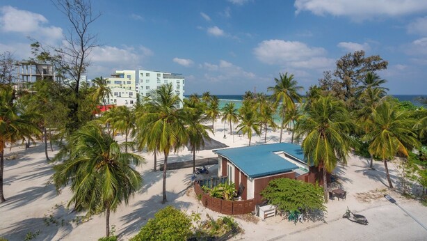 A beachfront property with a small building, palm trees, and a clear view of the ocean. - Express Inn (Hulhumalé)