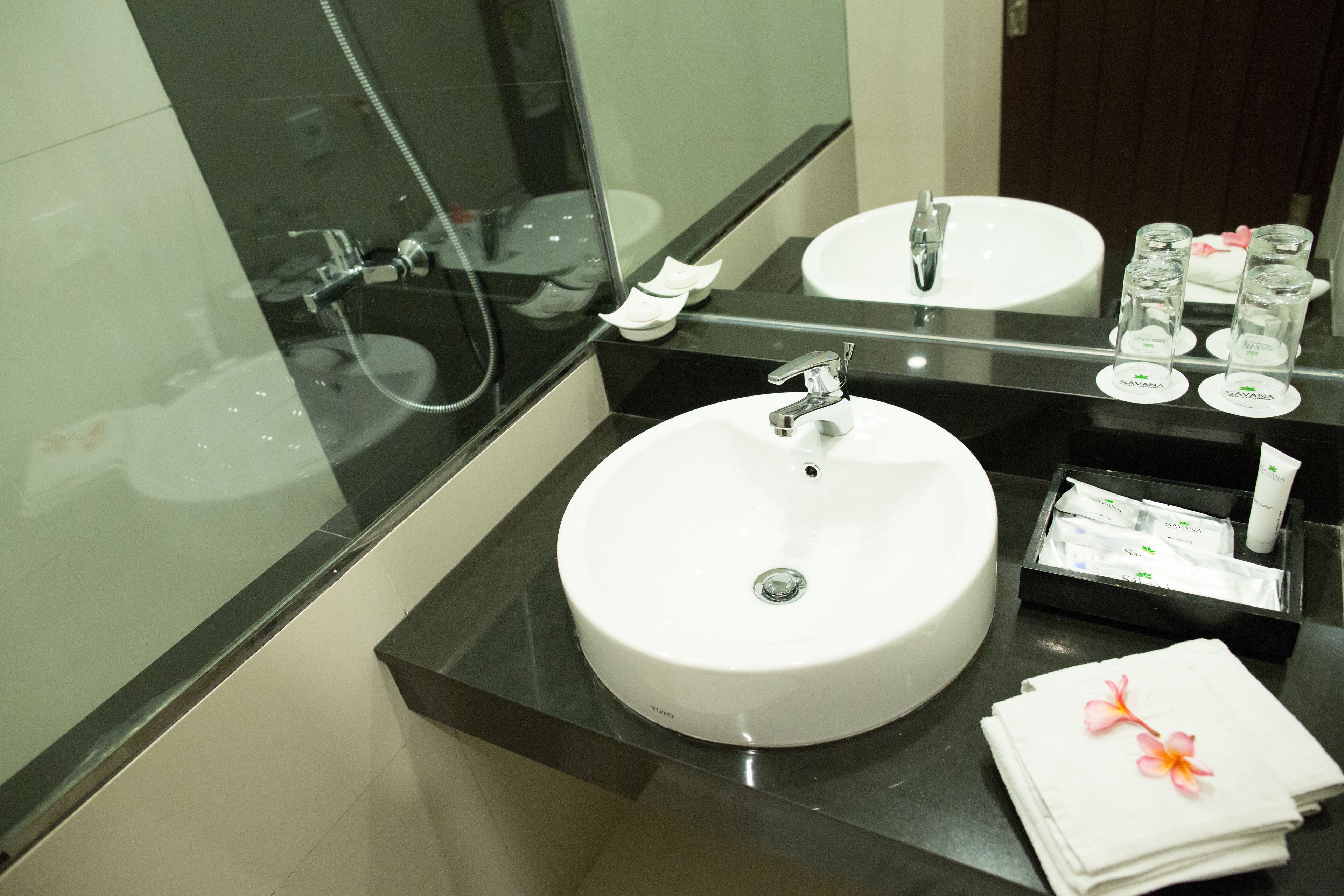 Un baño con un lavamanos blanco, un espejo y una cabina de ducha de cristal.