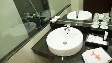 Un baño con un lavamanos blanco, un espejo y una cabina de ducha de cristal.