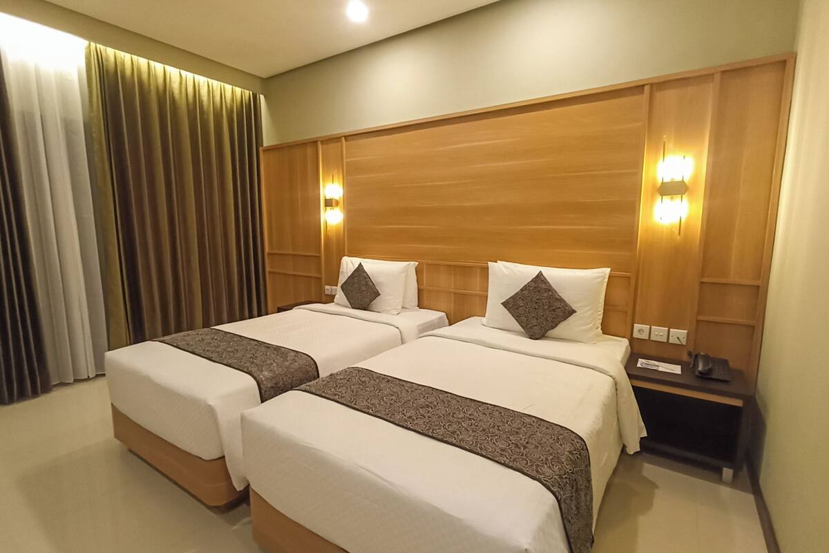 A hotel room with two beds, wooden headboards, and bedside lamps.