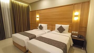 A hotel room with two beds, wooden headboards, and bedside lamps.