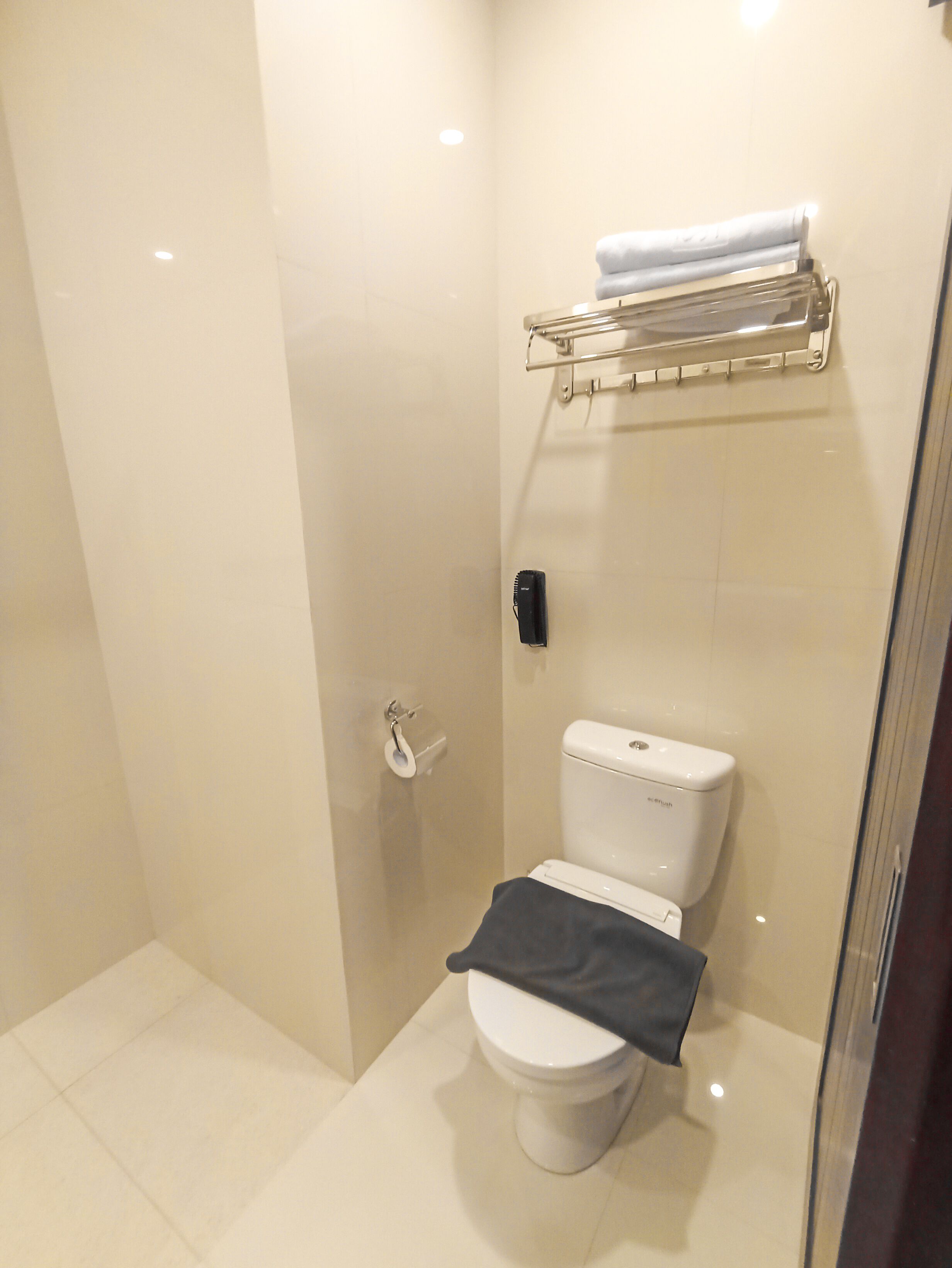 Un baño pequeño y moderno con inodoro, toallero y zona de ducha.