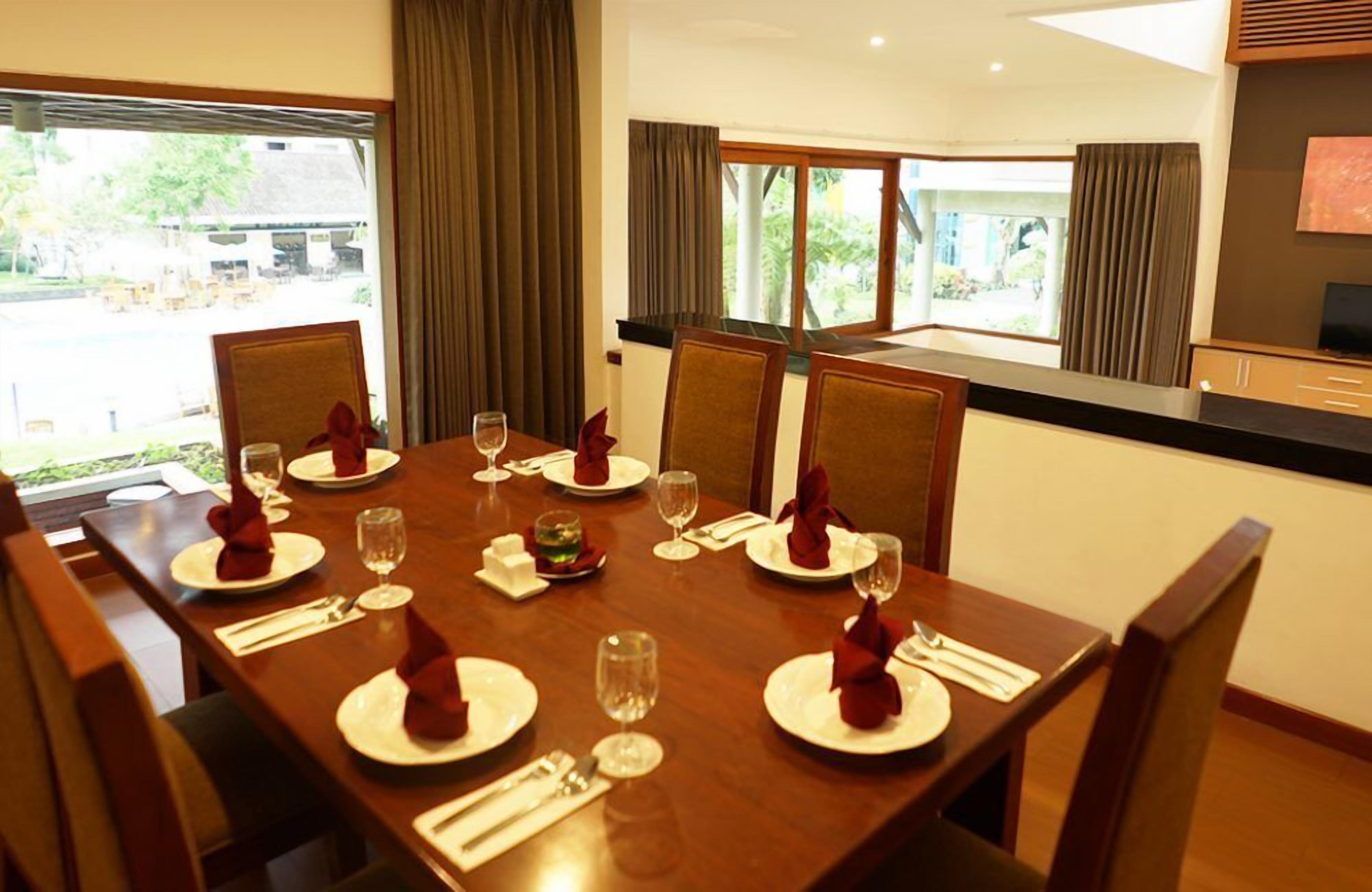 Un coin repas avec une table en bois mise pour six personnes, comprenant des assiettes, des verres et des couverts.