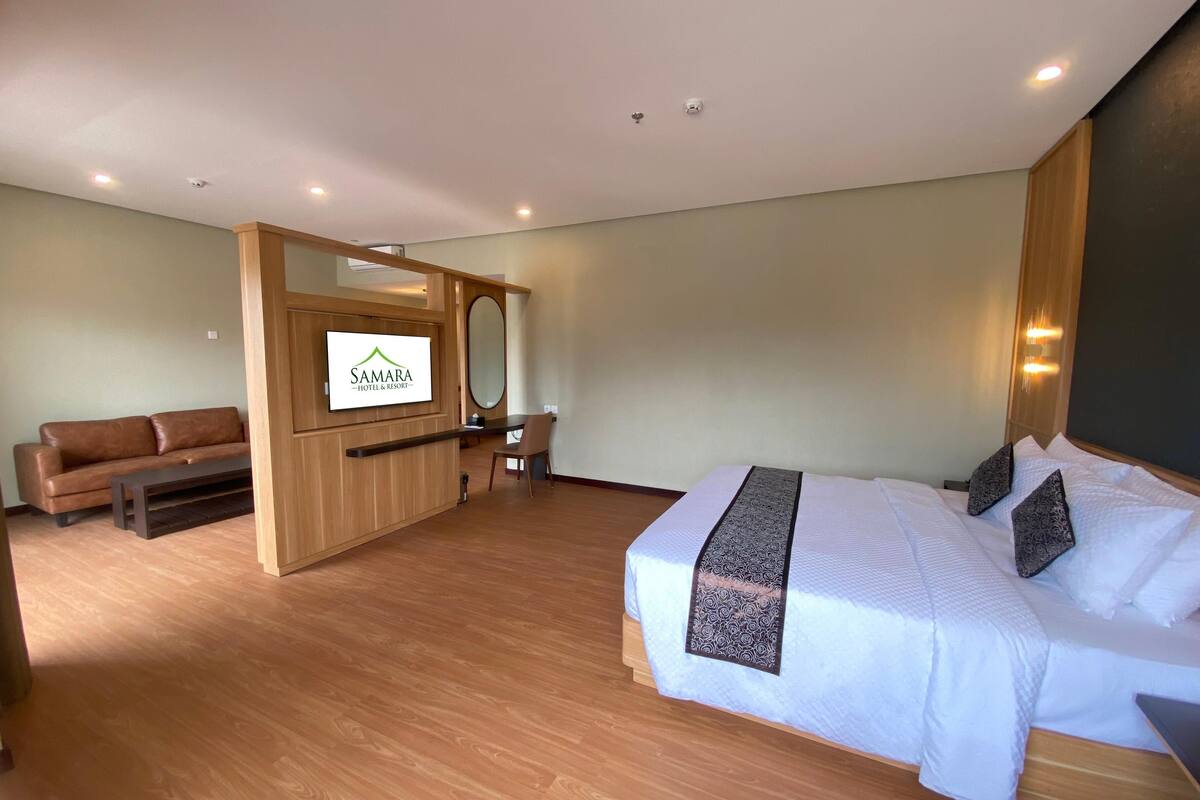 A hotel room with a bed, a sofa, a TV, and a desk.