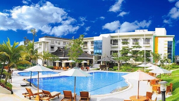 A resort with a swimming pool, lounge chairs, umbrellas, and a building with multiple floors and balconies. - Samara Resort (Batu)
