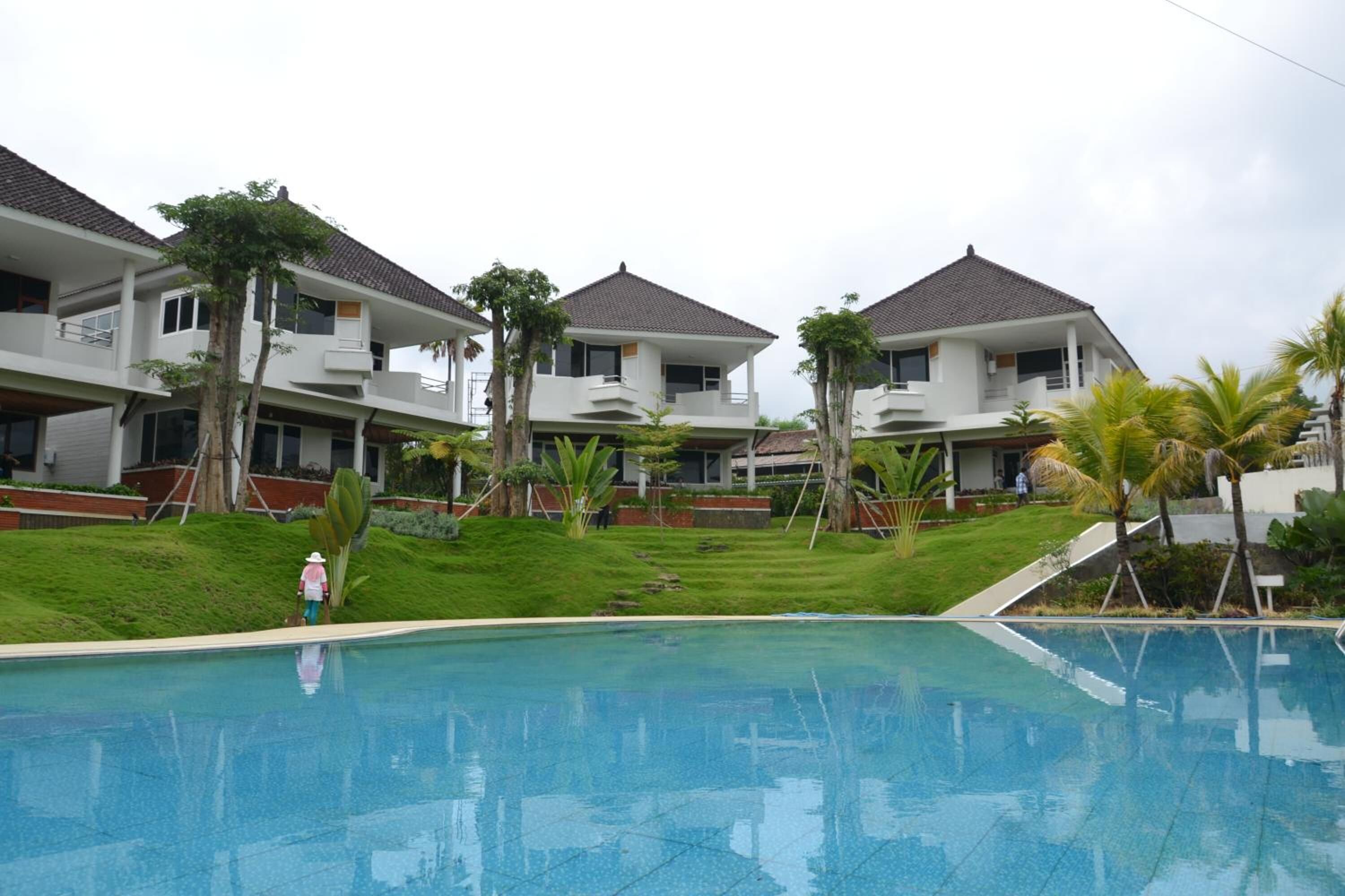 A residential complex with a swimming pool, multiple two-story buildings, and surrounding greenery.