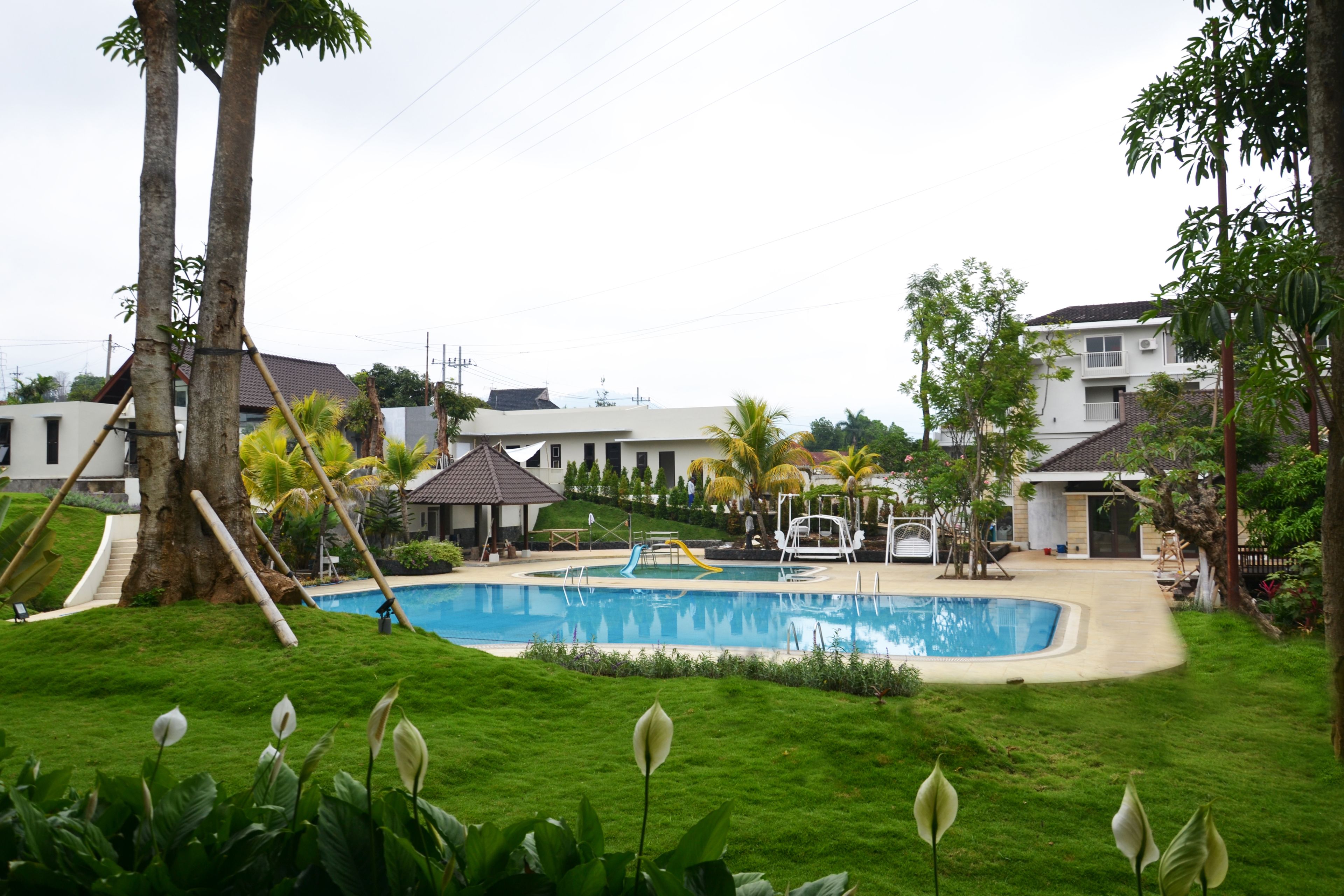 A swimming pool surrounded by lush greenery and residential buildings.