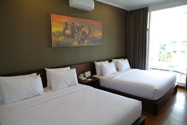 A hotel room with two beds, a painting of horses, and a view of the outdoors.