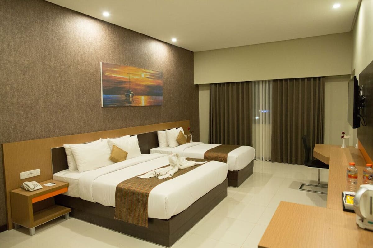 A hotel room with two beds, a desk, a telephone, and a painting on the wall.