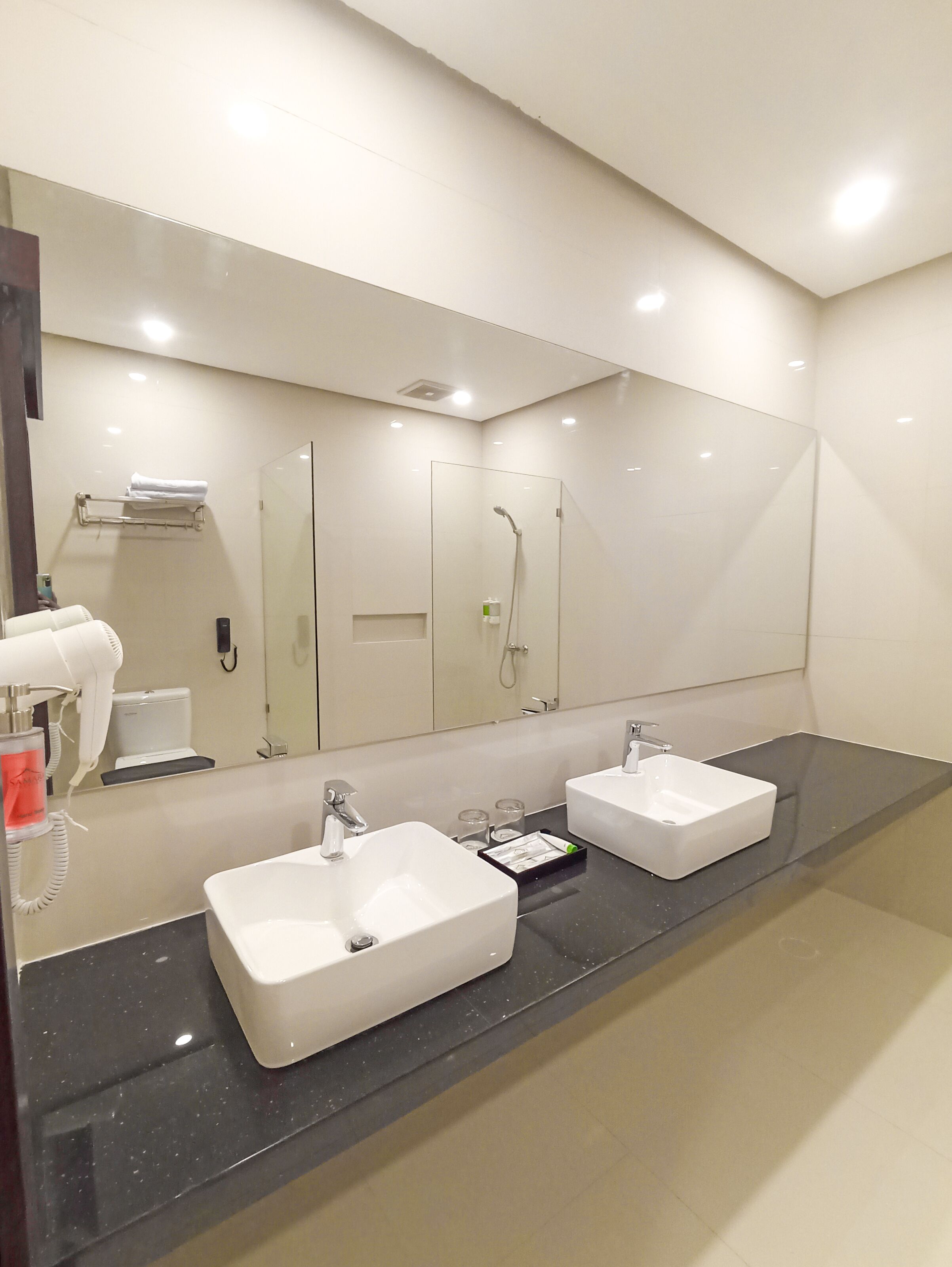 A modern bathroom with two sinks, a large mirror, and a glass shower enclosure.