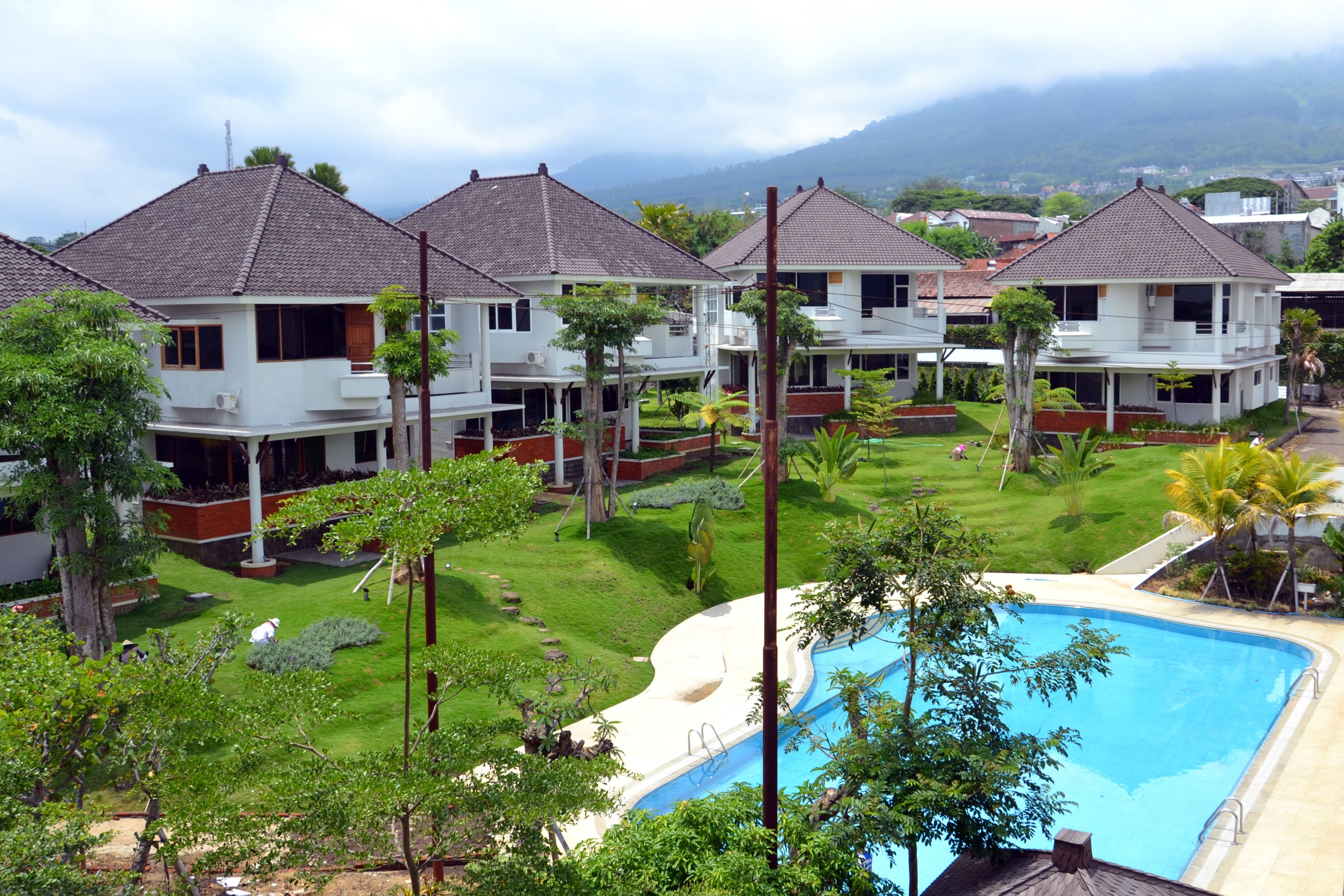 A residential area with multiple houses, a swimming pool, and lush greenery.