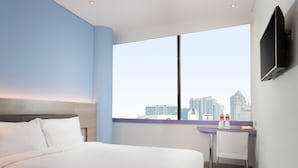 Habitació d'hotel moderna amb un llit gran, una taula de treball i una televisió penjada a la paret.