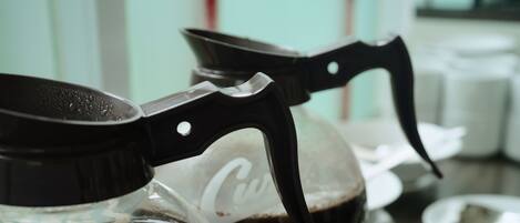 Una cafetera con un recipiente de vidrio y un asa negro.