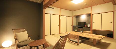 Ein traditioneller japanischer Raum mit Tatami-Bodenbelag, einem niedrigen Tisch und einem gepolsterten Sessel.