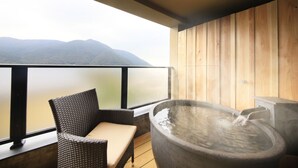 Un balcón con una silla de mimbre, un jacuzzi y vistas a las montañas.