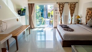 Habitación de hotel con cama, escritorio, silla, televisor y vistas al exterior.