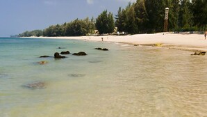 Una playa con agua cristalina, rocas y una orilla arenosa.