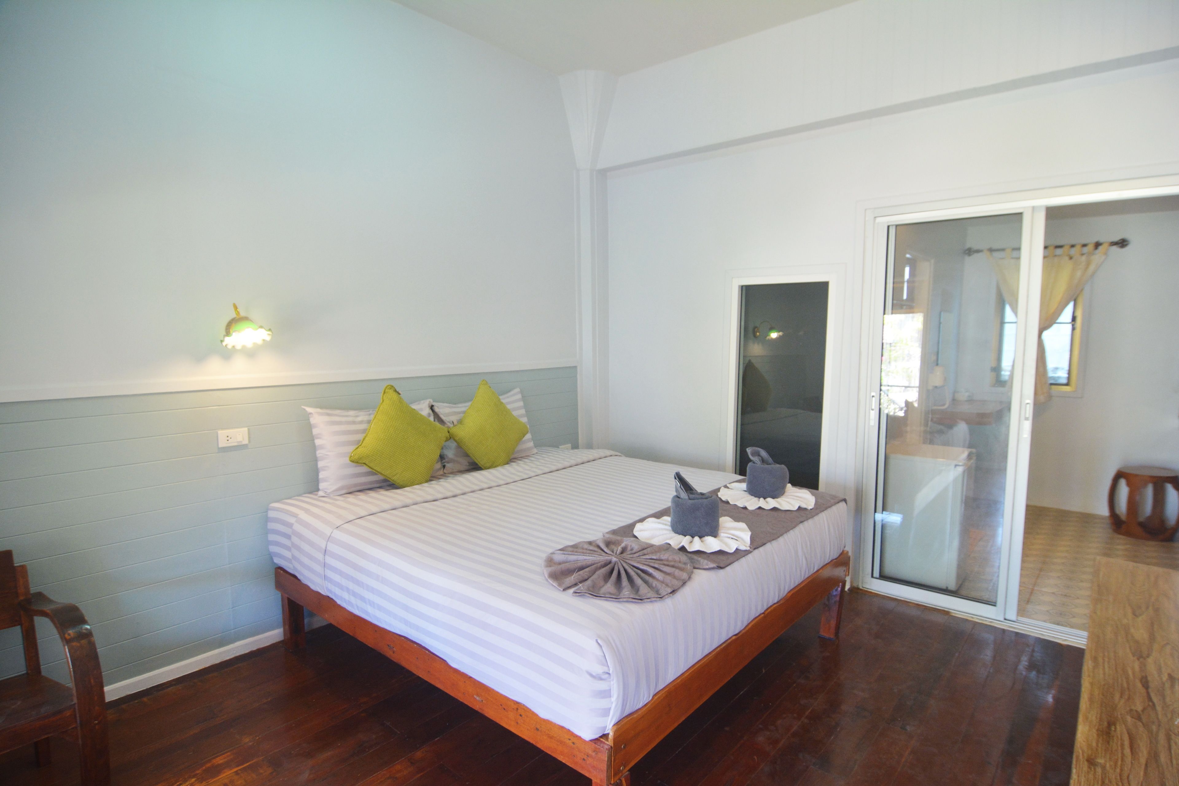 A bedroom with a bed, pillows, bedside table, and a sliding glass door leading to a balcony.