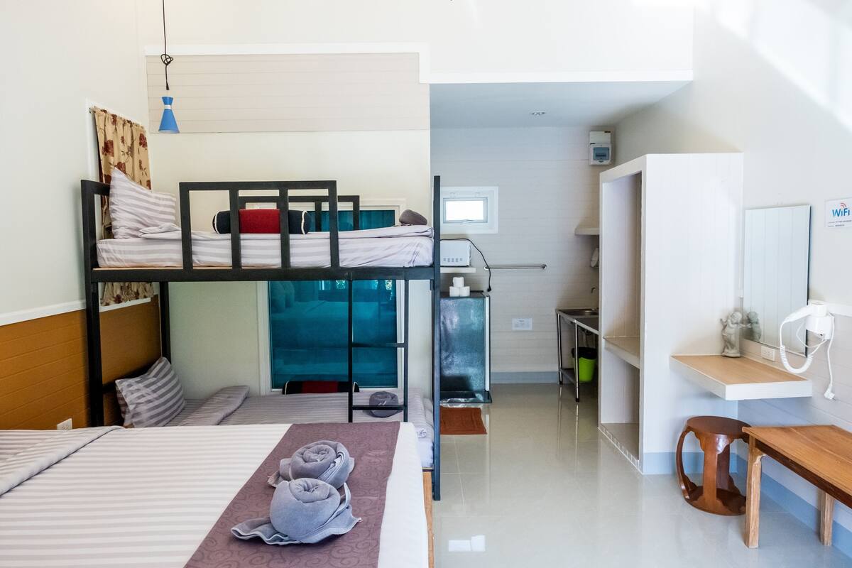 A dormitory room with bunk beds, a desk, a chair, and a small table.