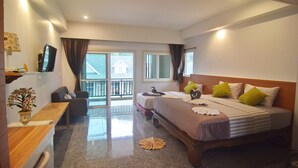 Habitación de hotel con cama, escritorio, silla, televisor y balcón con vista a una casa.