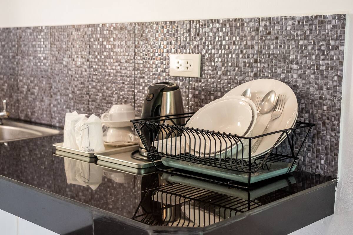 A kitchen with a dish rack, a coffee maker, and a sink.