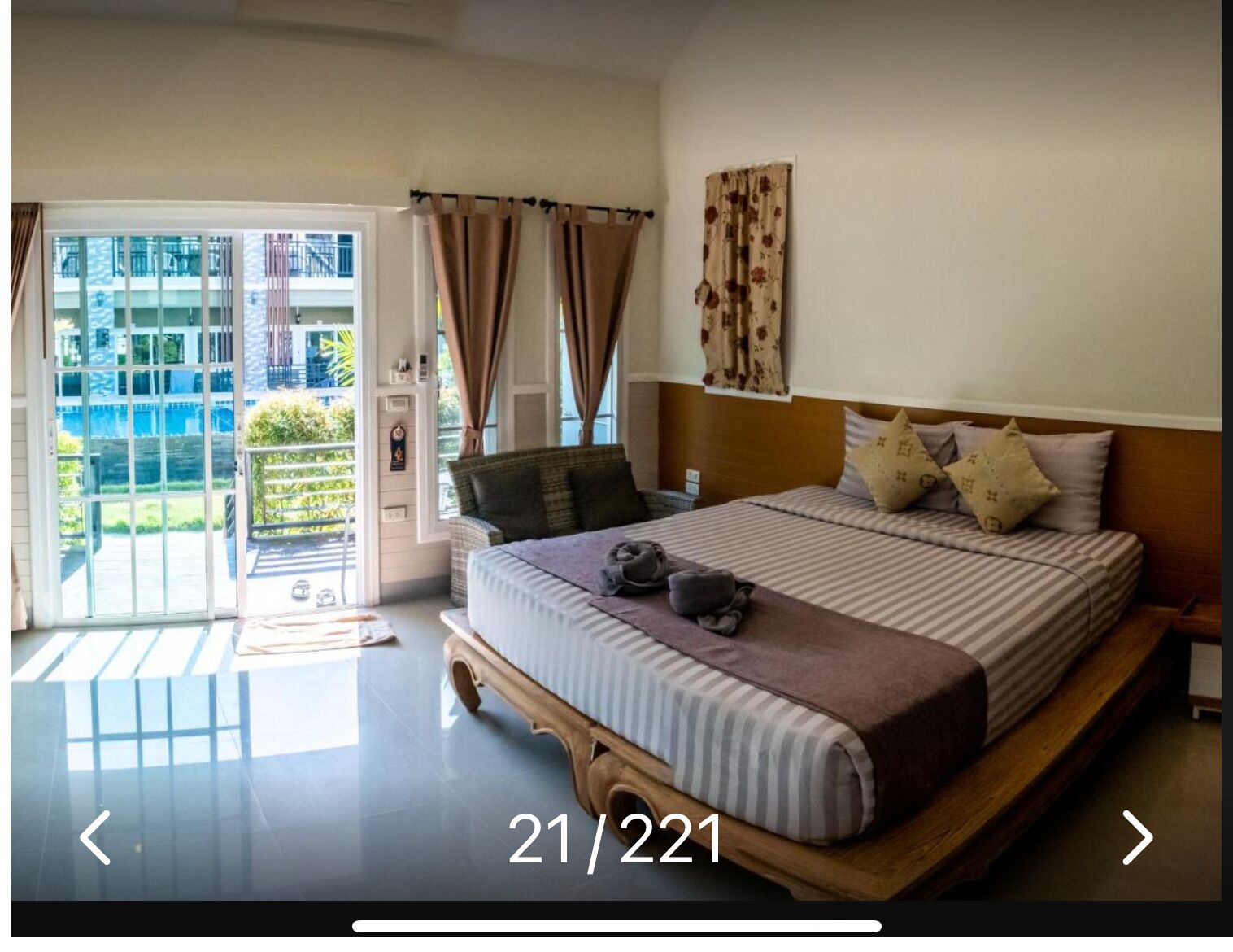 A hotel room with a large bed, a view of the outside balcony, and a sliding glass door.