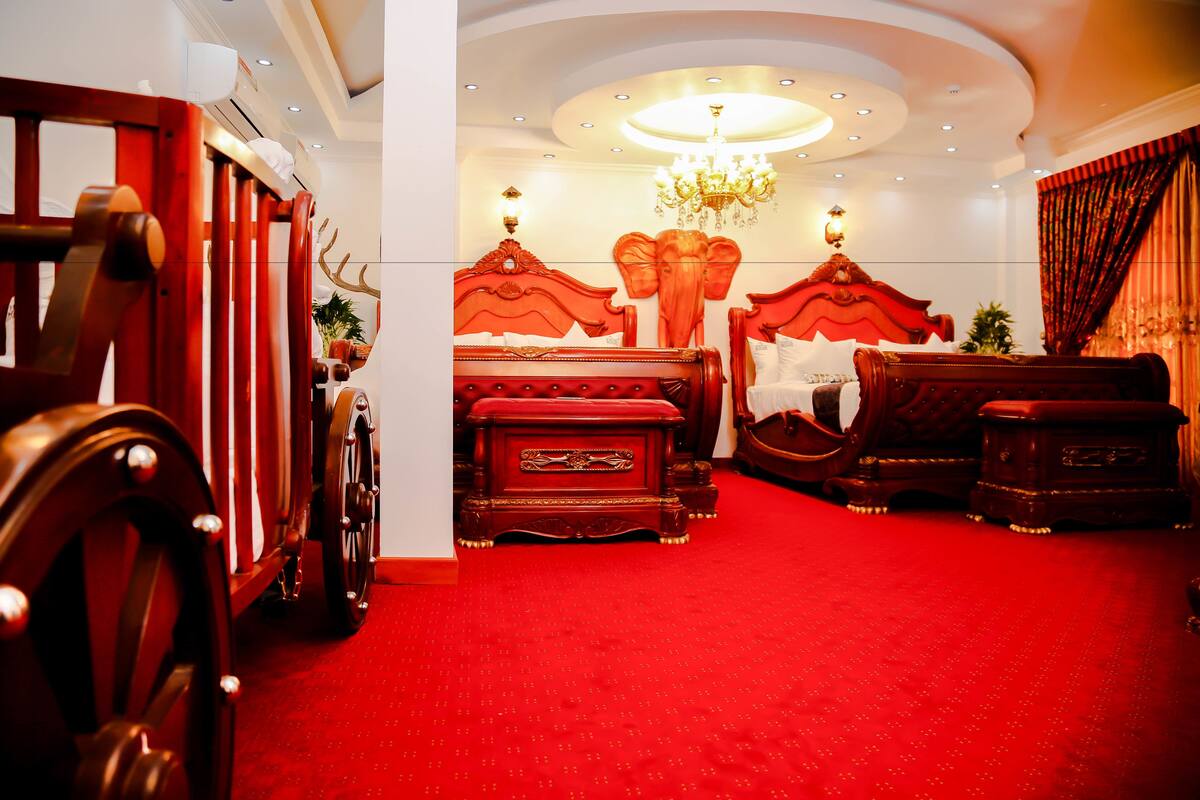 Une chambre à coucher luxueuse, avec un tapis rouge, un lit somptueux et un lustre.