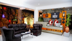 A reception area with a reception desk, two receptionists, a sofa, and a coffee table. - Hotel White House (Anuradhapura)