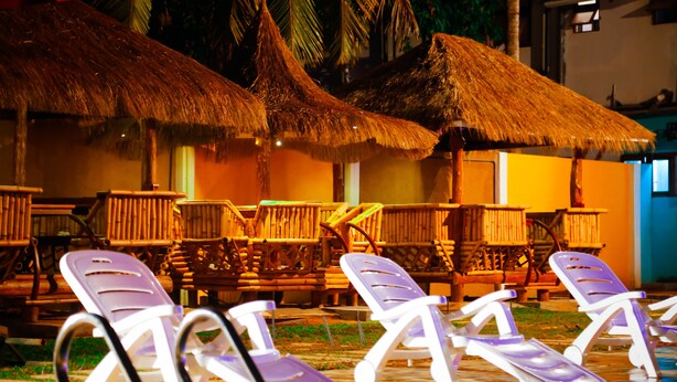 Outdoor lounge chairs and thatched umbrellas, suggesting a tropical resort setting. - Hotel White House (Anuradhapura)