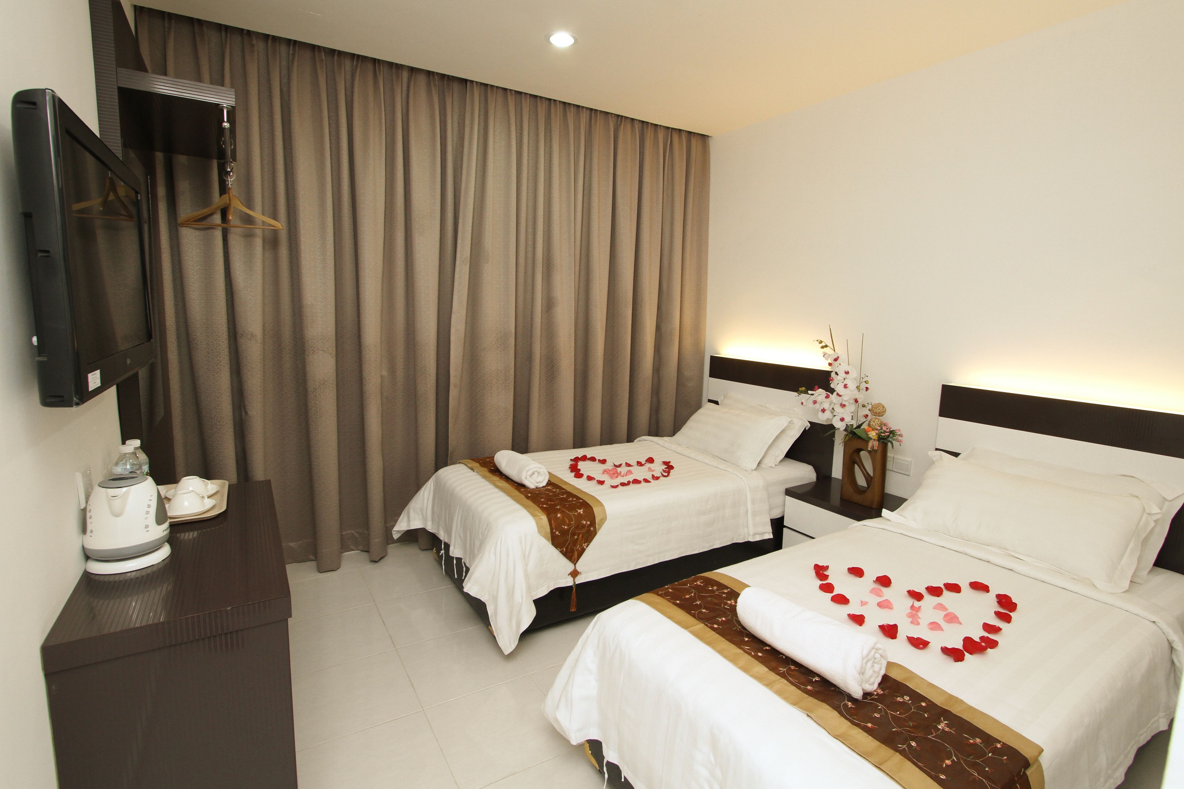 A hotel room with two beds, a TV, a coffee maker, and a curtain.