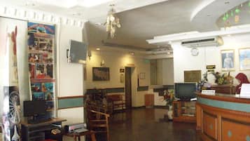 A hotel lobby with a reception desk, seating area, and a large poster on the wall.