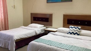 Una habitación de hotel con dos camas individuales, un cuadro en la pared, un equipo de aire acondicionado y un enchufe.