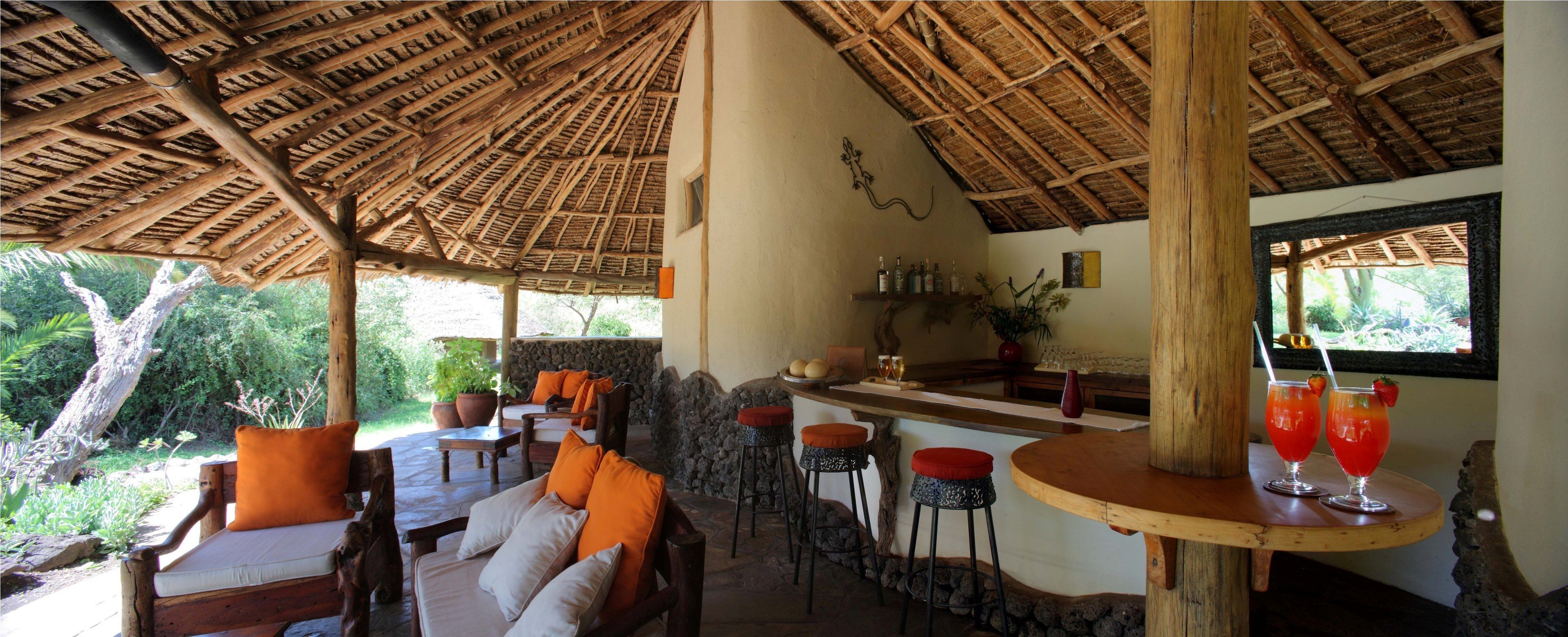 A rustic outdoor seating area with wooden furniture and a thatched roof.