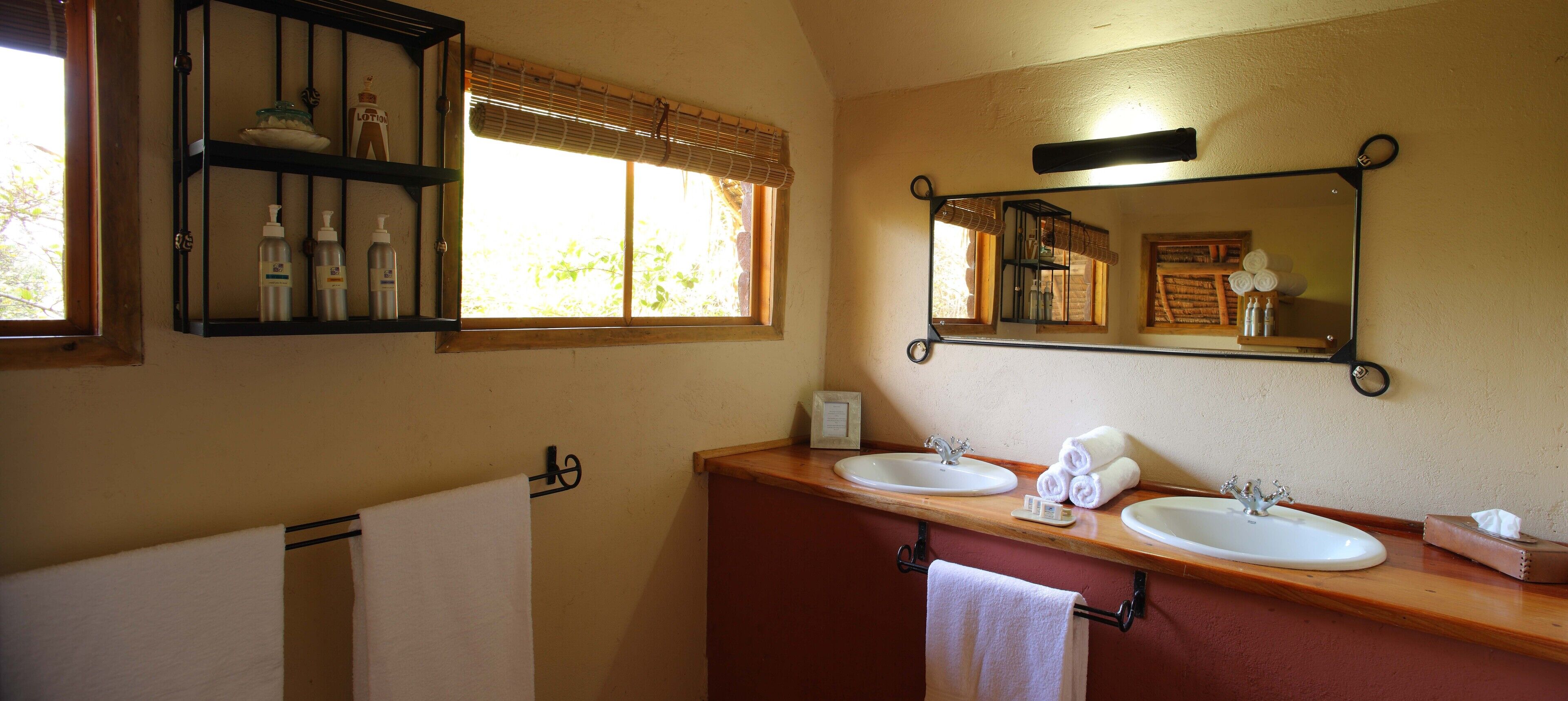 Un baño con dos lavamanos, un espejo y un estante con artículos de tocador.