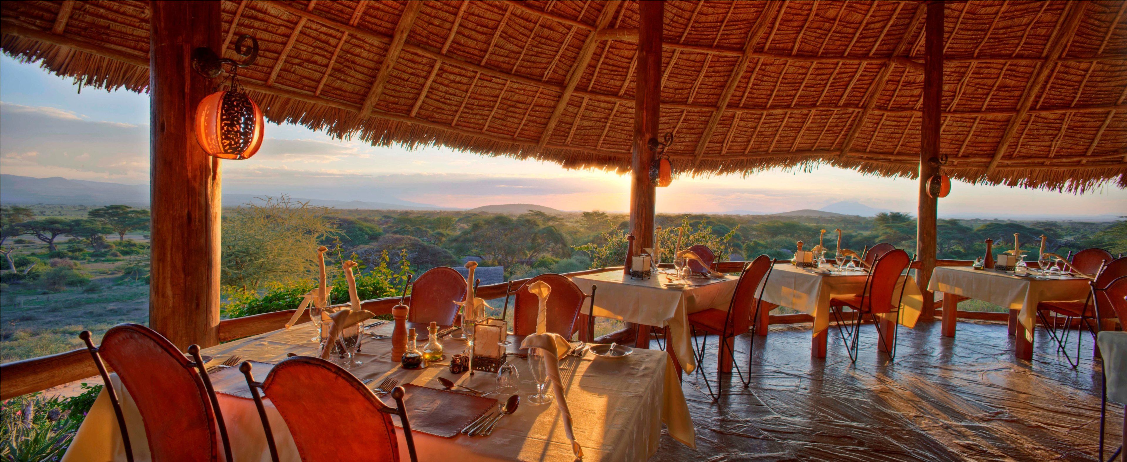 An outdoor dining area with tables set for a meal, overlooking a scenic landscape.