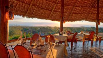 An outdoor dining area with tables set for a meal, overlooking a scenic landscape.