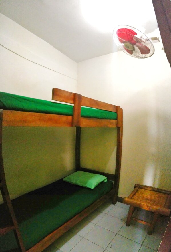 A bunk bed with a green mattress and a small wooden stool beside it.