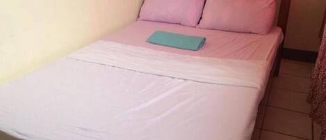 A single bed with a wooden headboard, white bedding, and two pillows.
